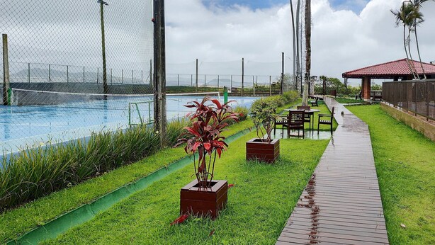 Zona de piscina con un deck de madera, césped verde y un pabellón de techo rojo.