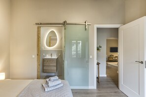 A bedroom with a bed, a bedside table, a mirror, a sliding door, and a bathroom visible through the door. - Casa 'Gall' with Mountain Views, Wi-Fi, and Air Conditioning (Espolla)