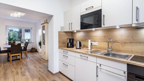 Eine moderne Küche mit weißen Schränken, einer Holz Arbeitsplatte, einer eingebauten Mikrowelle und einer Kaffeemaschine.