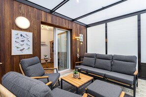 Un interior moderno con una pared de madera, un sofá, sillas, una mesa e ilustración enmarcada de un pájaro.