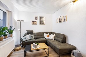 Una sala de estar moderna con un sofá modular, una mesa de centro y cuadros enmarcados en la pared.