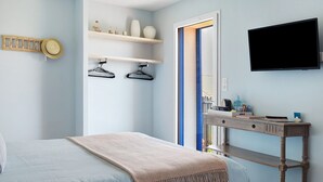 Un dormitorio con cama, un escritorio con televisor de pantalla plana y estantes con objetos decorativos.