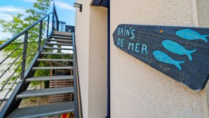 Una escalera que lleva a un edificio con un letrero que dice 'BAINS DE MER' y dos peces pintados.