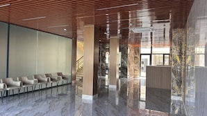 A modern lobby with a polished marble floor, wooden slatted ceiling, and a seating area with chairs. - HORIZON HOTEL (Tashkent)