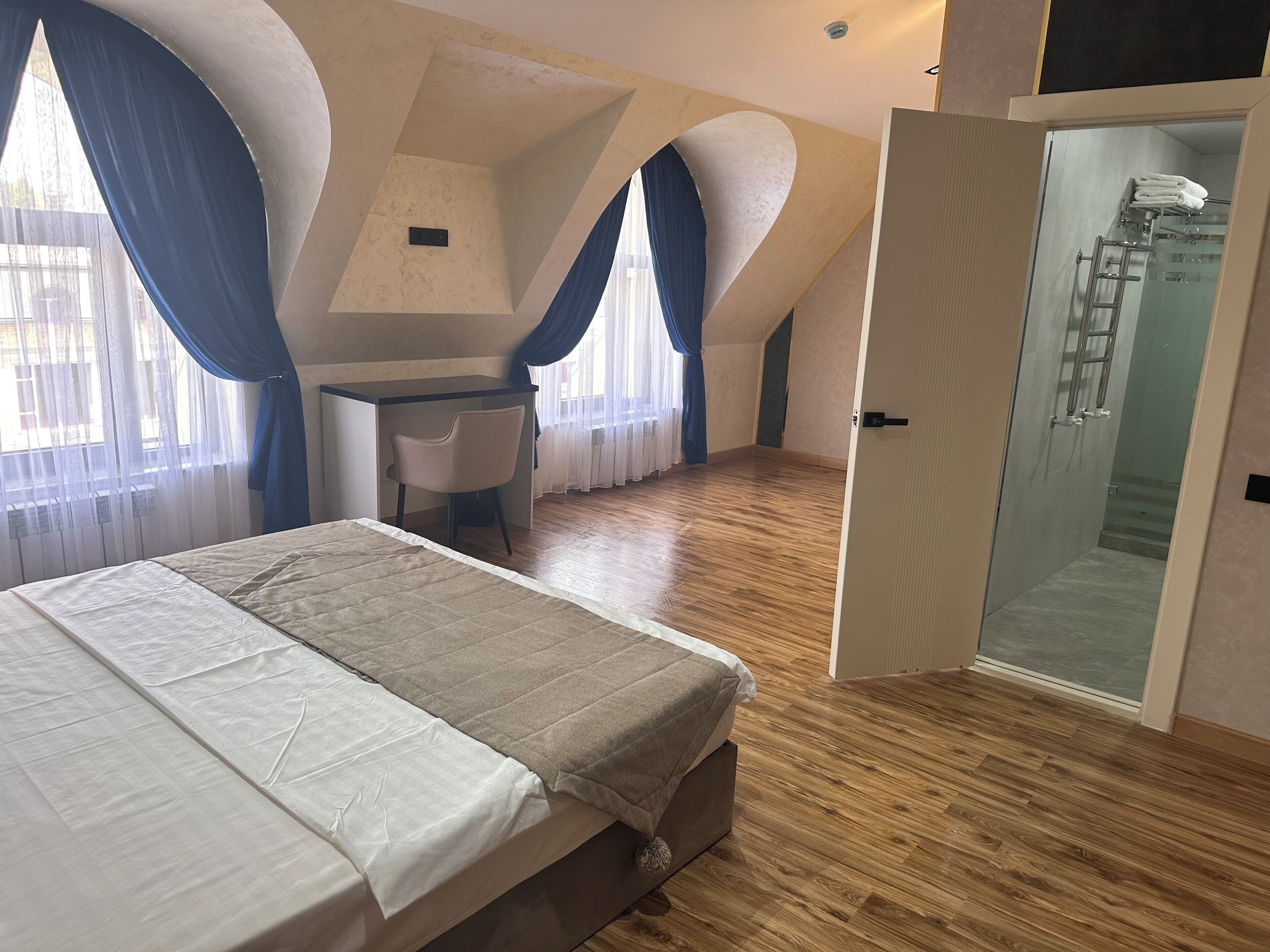 A bedroom with a bed, a desk, and a shower area.