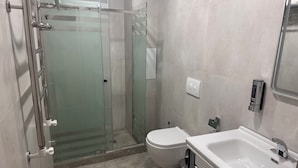 A modern bathroom with a glass shower enclosure, a toilet, and a sink with a mirror. - HORIZON HOTEL (Tashkent)