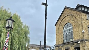 A street scene with a traditional brick building, a street lamp, and a CCTV camera.