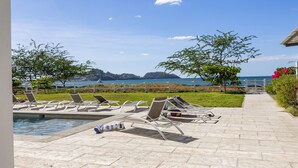 A poolside area with sun loungers and a view of the sea. - Beachfront Condo In Costa Rica (Tempate)