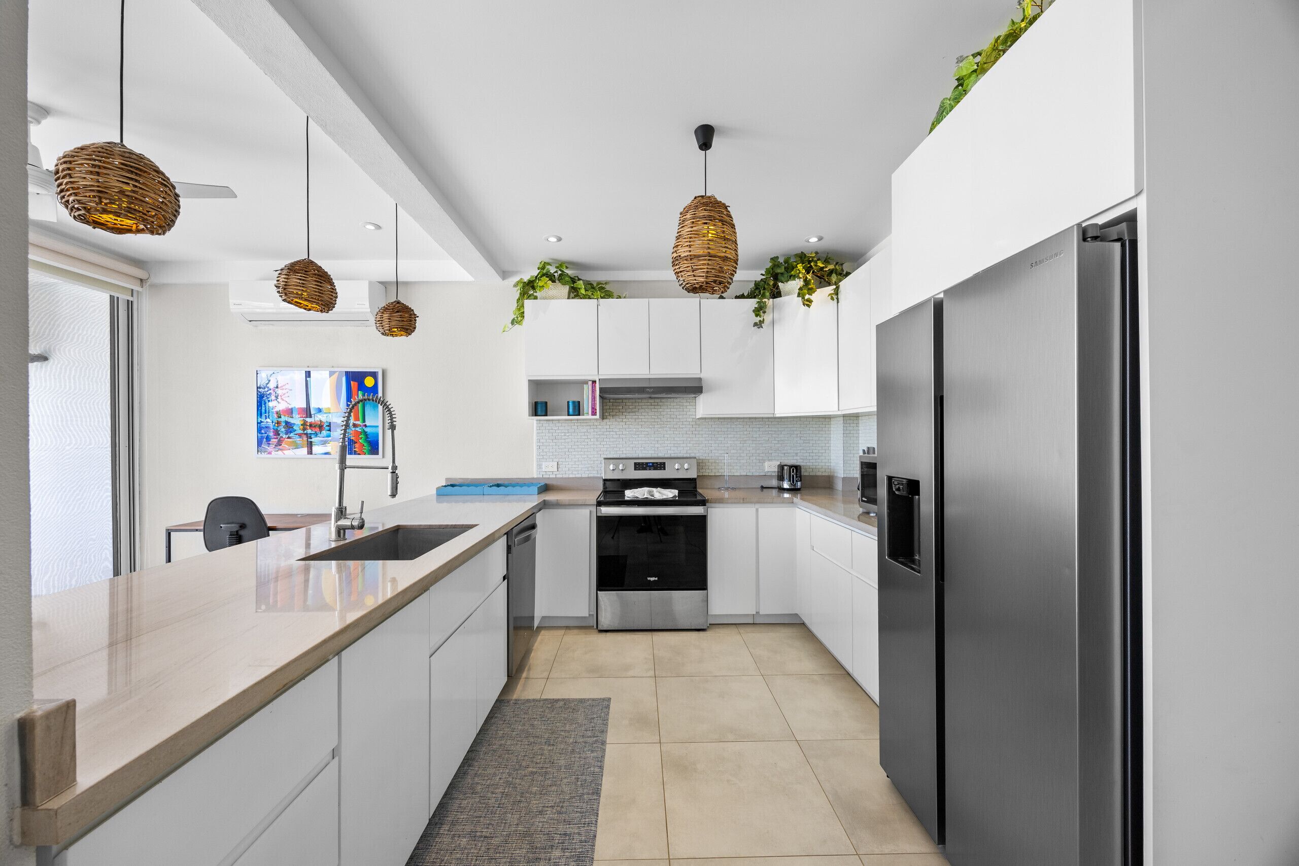 A modern kitchen with white cabinets, stainless steel appliances, and hanging wicker pendant lights.