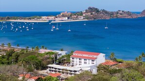 A coastal town with a marina, buildings, and a hilltop structure. - Beachfront Condo In Costa Rica (Tempate)