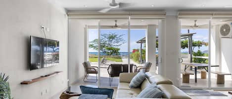 Sala de estar com sofá, televisão e vista para o exterior.