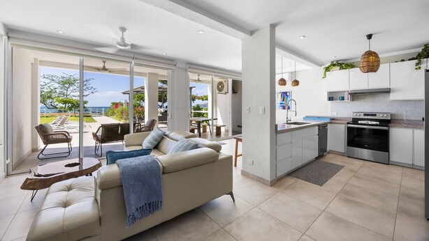 A modern kitchen with stainless steel appliances, a dining area with a table and chairs, and a living room with a sofa and a coffee table. - Beachfront Condo In Costa Rica (Tempate)