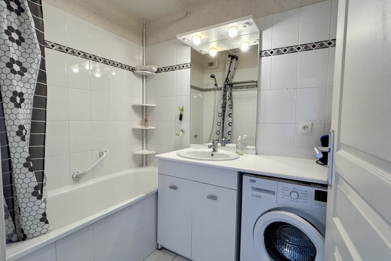 Une salle de bain équipée d’une baignoire, d’un lavabo, d’un miroir, d’une douche et d’un lave-linge.