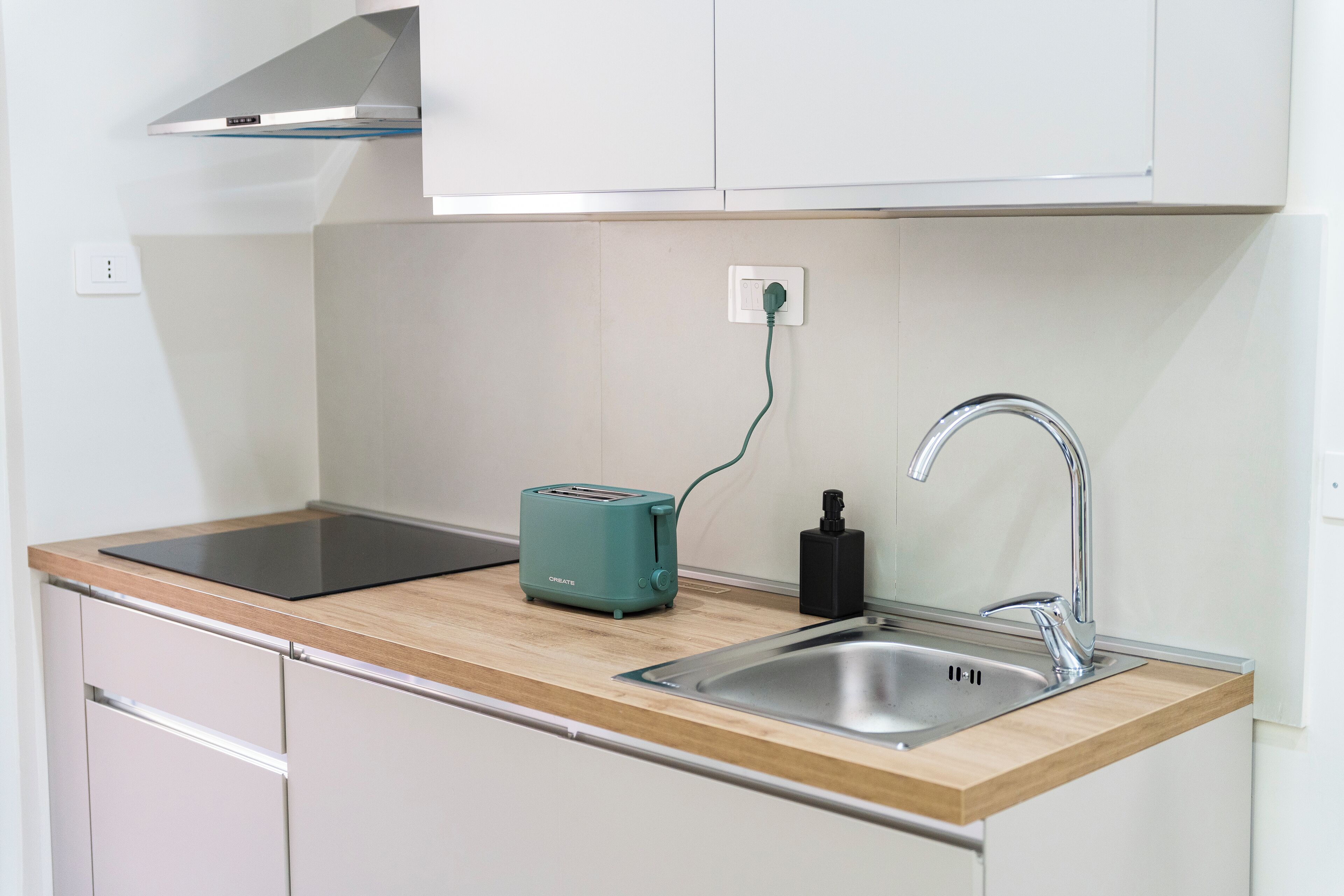 A modern kitchen with a built-in toaster, a sink, and a stove.