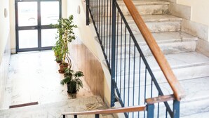 A staircase with marble steps and a wooden handrail, leading to a door with a view of the outside. - N'ador Rooms (Naples)