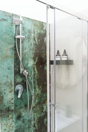 A shower with a handheld showerhead and a wall-mounted faucet. There are two bottles on a shelf above the shower. - N'ador Rooms (Naples)