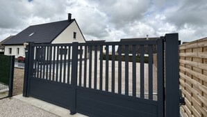 En inhägnad fastighet med en vit byggnad och ett svart tak.