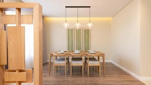 A dining area with a wooden table and chairs, a hanging light fixture, and decorative wall panels.