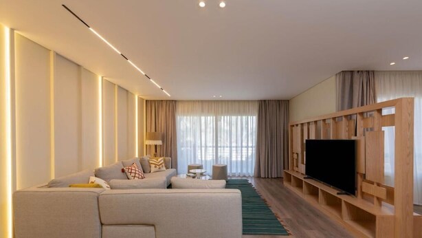 A modern living room with a sofa, a television, and a wooden entertainment unit.