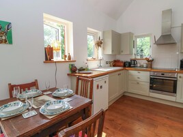 A kitchen with wooden cabinets, a built-in oven, and a dining area with a wooden table set for four.