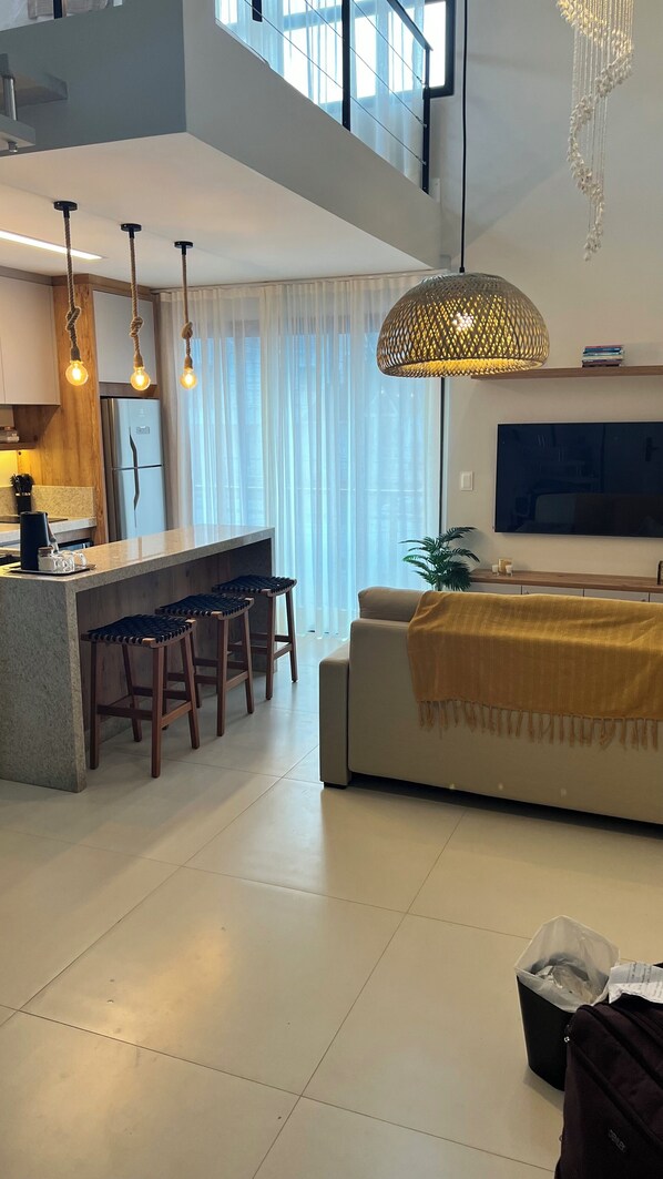 Una cocina moderna con una isla central, taburetes de bar e iluminación colgante.
