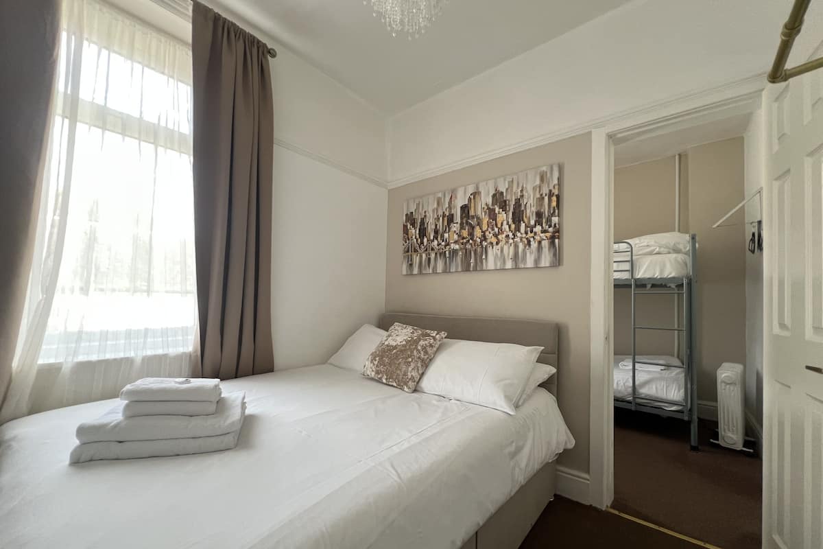 Una habitación de hotel con cama, un cuadro, literas y un radiador.