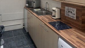 Una cocina moderna con armarios de madera, microondas integrado, pileta y cafetera.