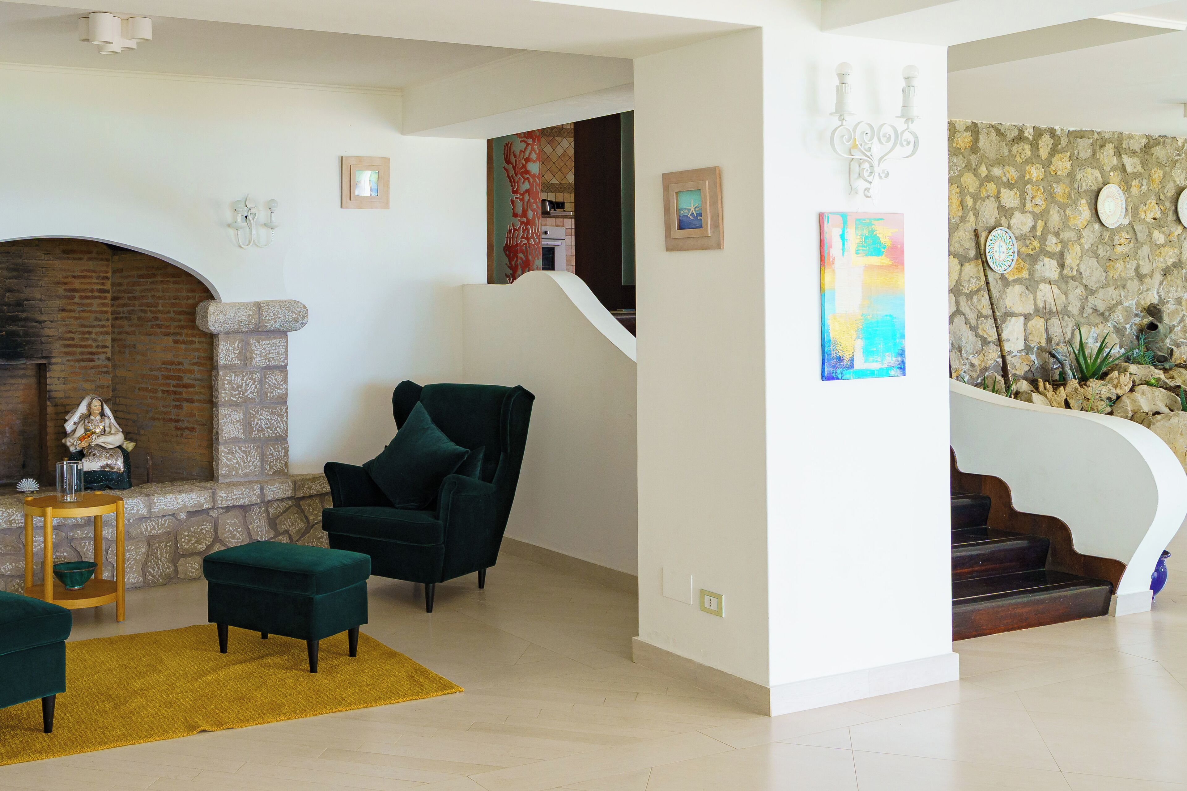 A living room with a fireplace, a staircase, and a stone wall.