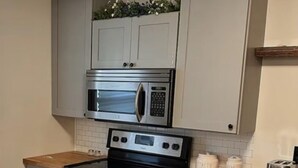 A kitchen with a microwave, oven, and wooden countertop. - Adorable 2-bedroom Farmhouse in beautiful Lake Guntersville (Guntersville)