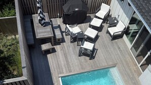 Une terrasse avec une piscine, du mobilier d’extérieur et un espace barbecue couvert.