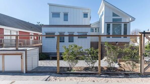 A modern two-story house with a white exterior and a fenced backyard. - Beach house just steps from the Ocean, in Ocean Beach (Ocean Beach)