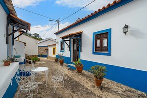 A narrow street with white and blue buildings, outdoor seating, and potted plants. - Villa 'Terra' with Private Terrace, Shared Garden and Wi-Fi (Monchique)