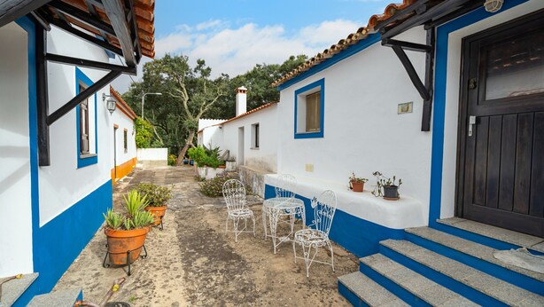 A narrow alleyway with white walls and blue trim, potted plants, and metal chairs. - Villa 'Terra' with Private Terrace, Shared Garden and Wi-Fi (Monchique)