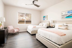 A bedroom with a large bed, a smaller bed, a chair, a desk, and a window with a view.