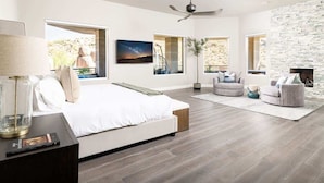 Un dormitorio moderno con cama, zona de estar y chimenea.