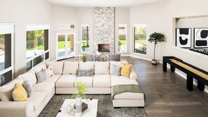 Amplia sala de estar con un sofá seccional grande, chimenea y ventanas amplias que ofrecen vistas al exterior.