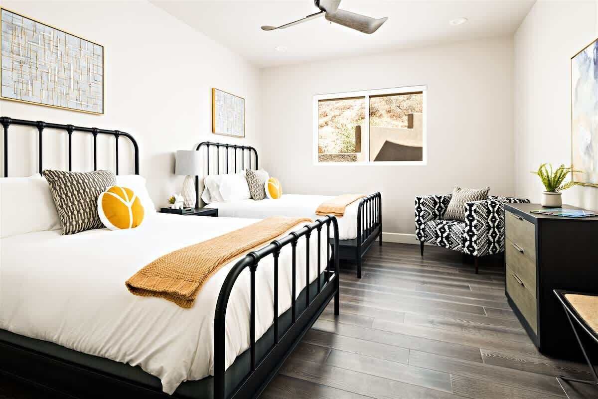 Een slaapkamer met twee bedden, een bureau, een stoel en een plafondventilator.