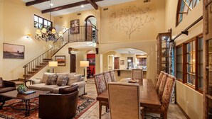 A spacious living area with a staircase, a dining table with chairs, and a chandelier.