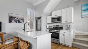 A modern kitchen with white cabinetry, a built-in oven, and a stainless steel refrigerator.