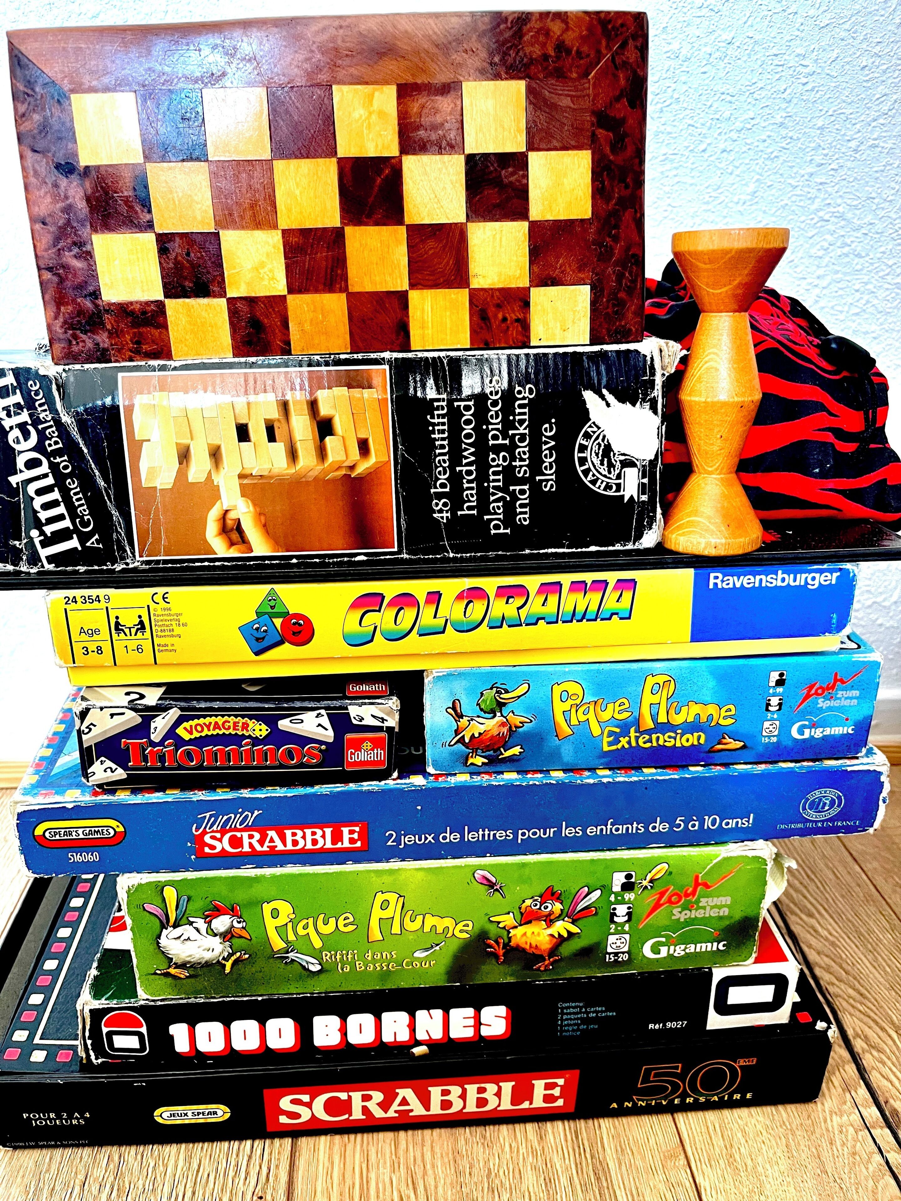 A stack of various board games including Scrabble, Pique Plume, and others.