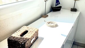 A white shelf with a woven basket, a small sailboat model, and a bird figurine.