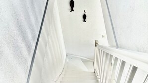 A white staircase with a railing, leading to a landing with two wall-mounted light fixtures.