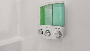 A wall-mounted dispenser with three compartments labeled shampoo, conditioner, and body wash.