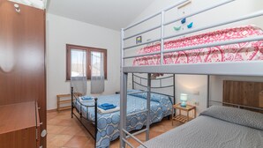 Une chambre de dortoir avec des lits superposés, une armoire en bois, une fenêtre avec des rideaux et une table de chevet avec une lampe.