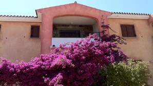 Un bâtiment doté d’un balcon, d’un mur en pierre et orné de fleurs de bougainvillier roses.