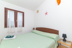 A bedroom with a bed, a window with curtains, a star decoration, a lamp on a bedside table, and a towel on the bed. - Apartment 'Posada' with Sea View, Wi-Fi and Air Conditioning (Posada)