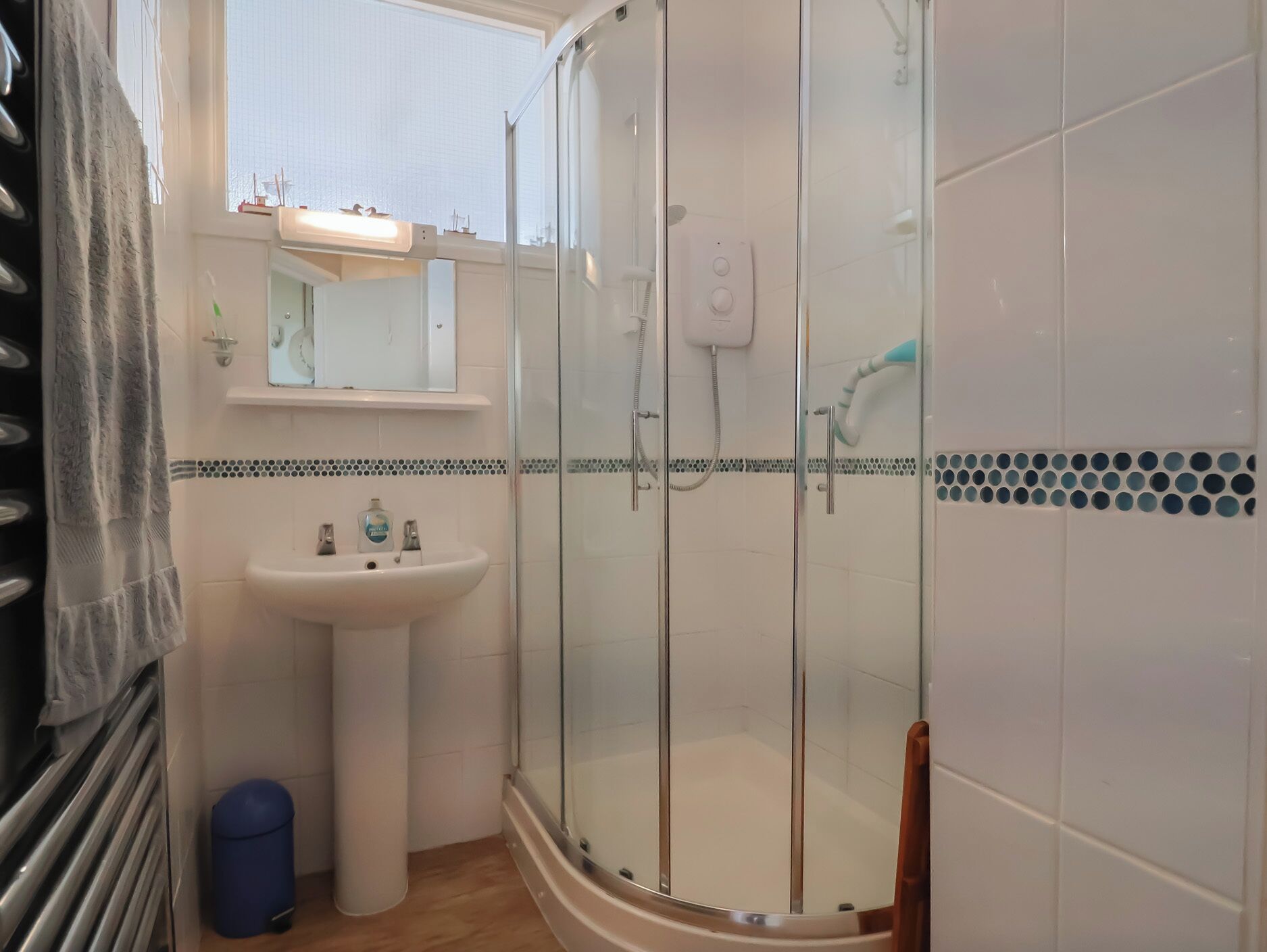 A bathroom with a glass-enclosed shower, a white sink, and a mirror above it.