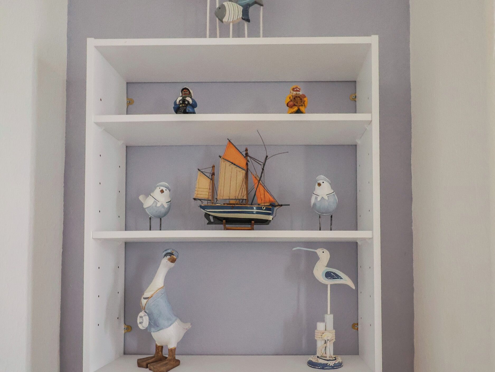 Una estant blanca de tres nivells, cadascun amb objectes decoratius diferents.