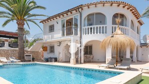 Un edificio de dos pisos con piscina, asientos al aire libre y una palmera.