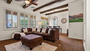 A spacious living room with a sectional sofa, a coffee table, and a dining area with a chandelier. - LV366 3BR Desert Villa with Views & 2 Primary Suites (La Quinta)